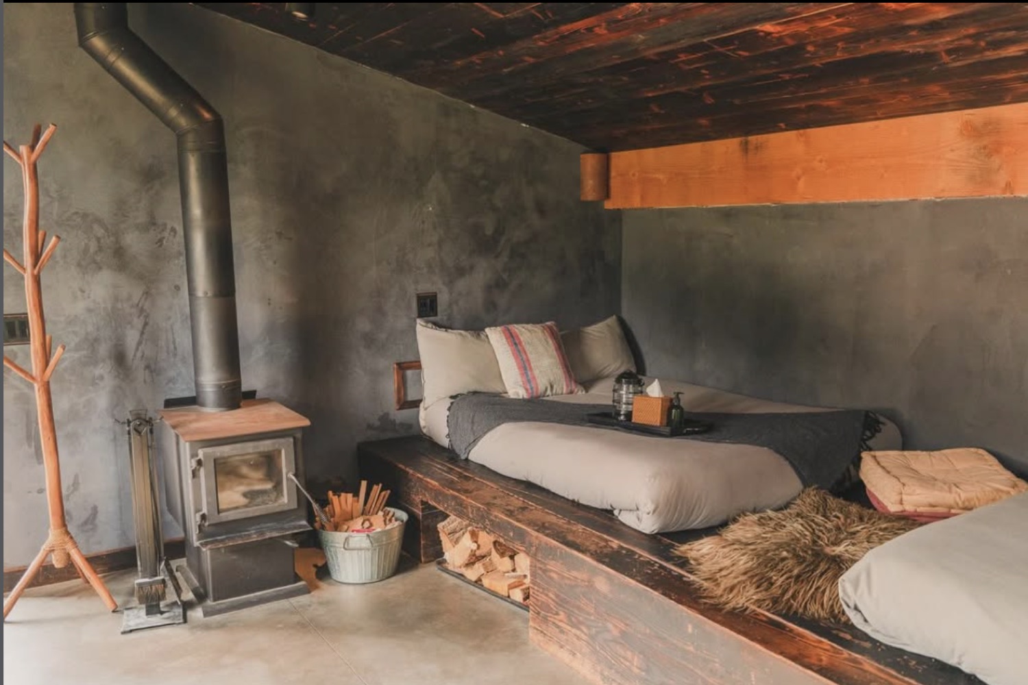 Cabin bedroom with a wood-burning stove and platform bed